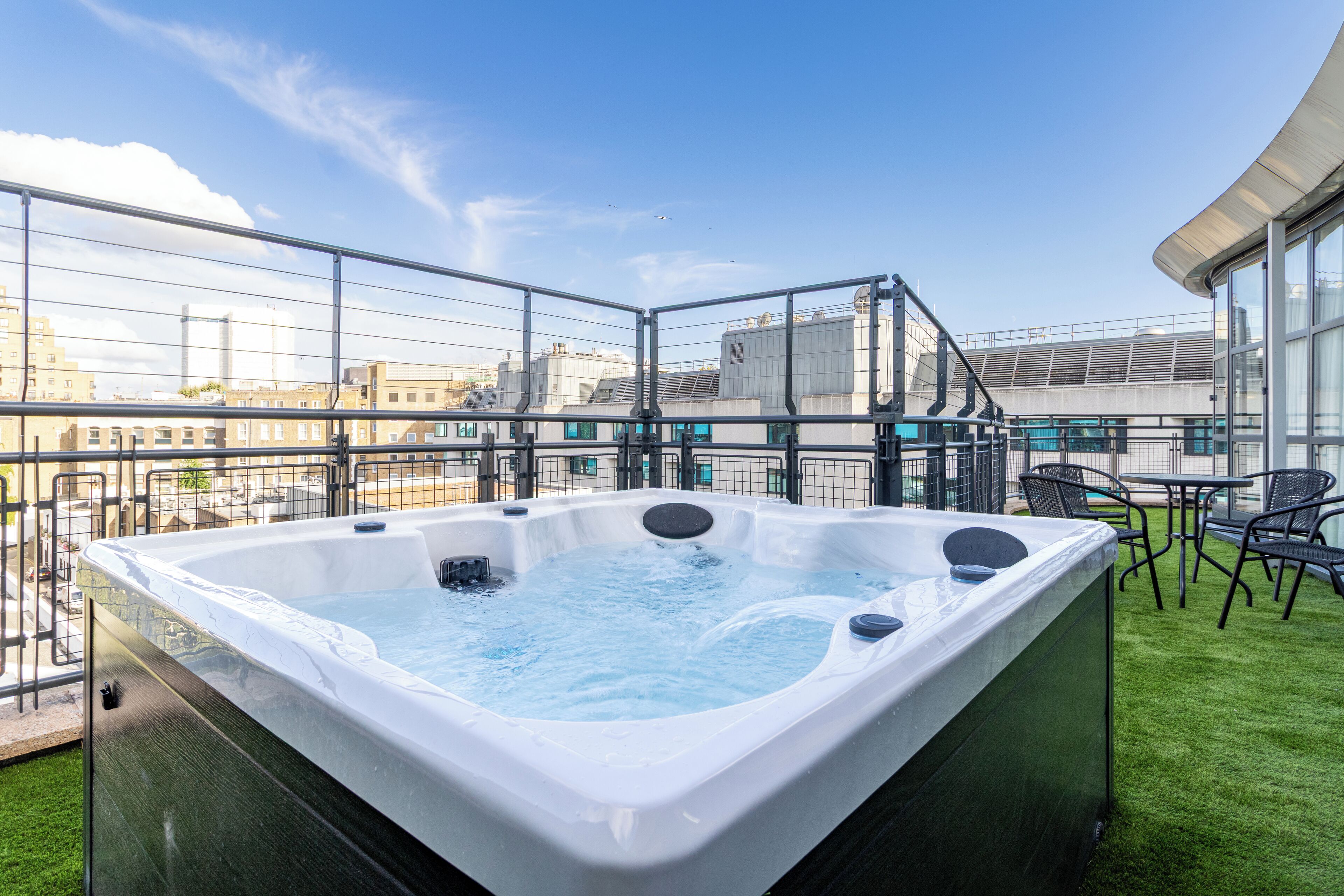 Un jacuzzi en una terraza en la azotea con vistas al horizonte de la ciudad.