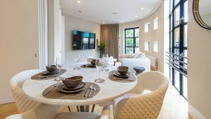 A modern dining area with a round table set for four, surrounded by cushioned chairs. - AYLI (London)