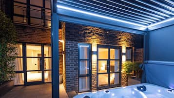 A modern hotel with a glass door entrance, a hot tub, and a brick facade.