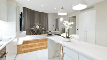 A modern kitchen with white cabinetry, a wooden countertop, and a dining area with a table and chairs.