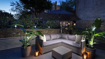 A modern outdoor seating area with a sectional sofa, a coffee table, and potted plants.