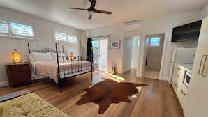 A bedroom with a bed, bedside table, lamp, and a ceiling fan. - Spacious Byron Central Studio Apartment w/ Private Balcony (Byron Bay)