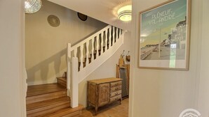 A wooden staircase with white balusters, a wooden cabinet, and a framed picture of Plénéeuf-Valrandré. - Les Pâquerettes - PLENEUF VAL ANDRE (PLENEUF VAL ANDRE)