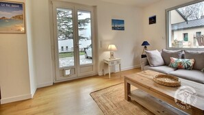 A living room with a sofa, coffee table, and a view through a glass door. - Les Pâquerettes - PLENEUF VAL ANDRE (PLENEUF VAL ANDRE)