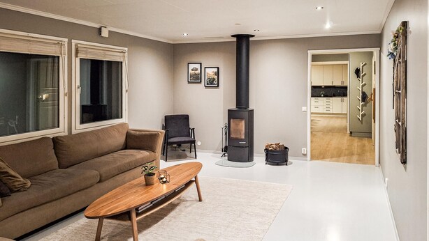 A modern living room with a sofa, a wooden coffee table, a fireplace, and a view into the kitchen.
