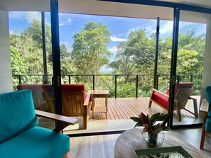 A balcony with wooden furniture and a view of lush greenery. - Sinfonía Tropical, ocean view, 5 minutes drive to Playa Linda, 15 to Dominical, wifi Starlink (Savegre de Aguirre)