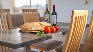 Une table à manger avec une miche de pain, des tomates et des bouteilles de vin.