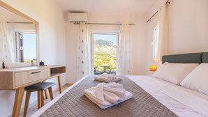 Une chambre d’hôtel équipée d’un lit, d’un bureau, d’une chaise, d’un miroir et d’une fenêtre donnant sur les montagnes.