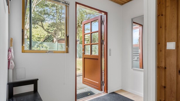Una habitación con puerta de madera, una ventana y un pequeño banco.