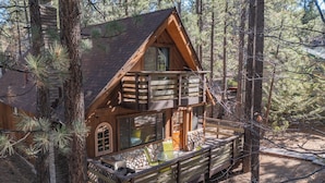A cabin with a stone foundation, a balcony, and a stone wall.