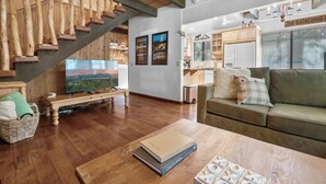 A spacious living area with a wooden staircase, a television, a sofa, and a coffee table.