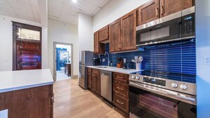 Une cuisine moderne avec des meubles en bois, des appareils électroménagers en acier inoxydable et un pare-feu bleu.