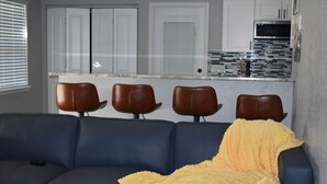 Ein Wohnzimmer mit einem blauen Sofa, einer gelben Decke und vier braunen Stühlen.