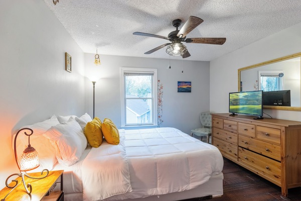 Cozy queen bedroom with plush bedding, natural light, and ample closet space.