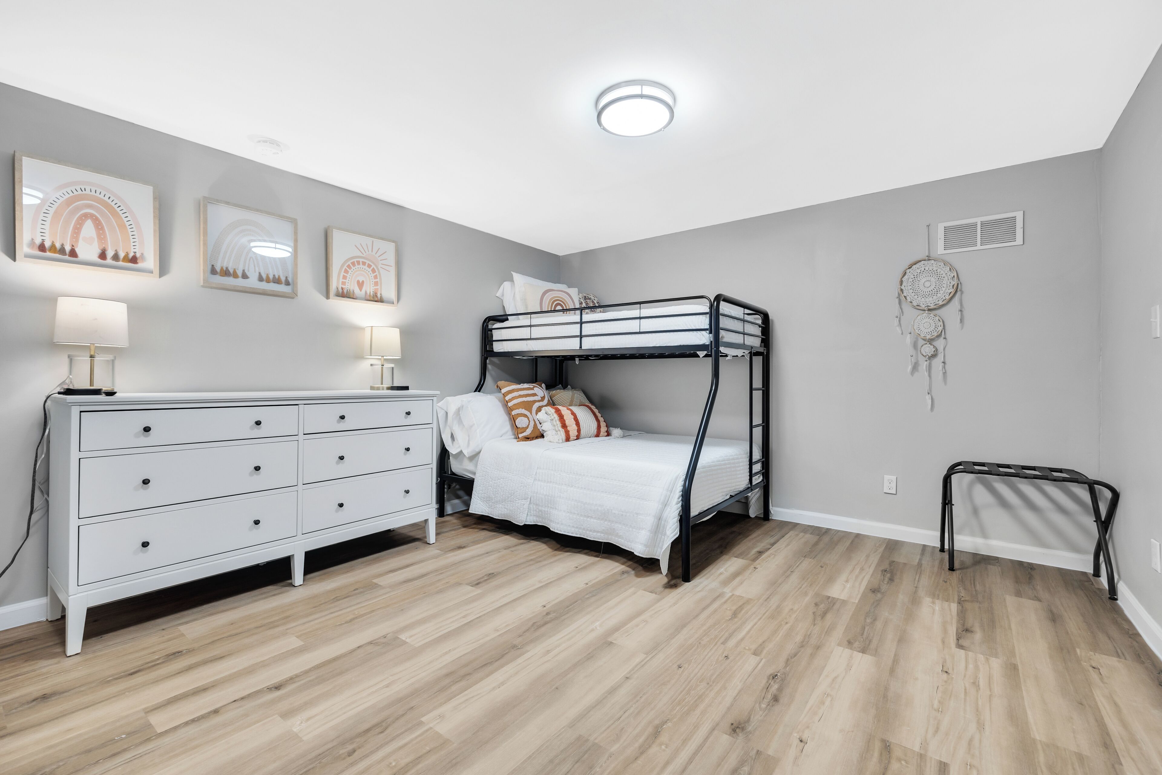 Een slaapkamer met een stapelbed, een dressoir en wanddecoratie.