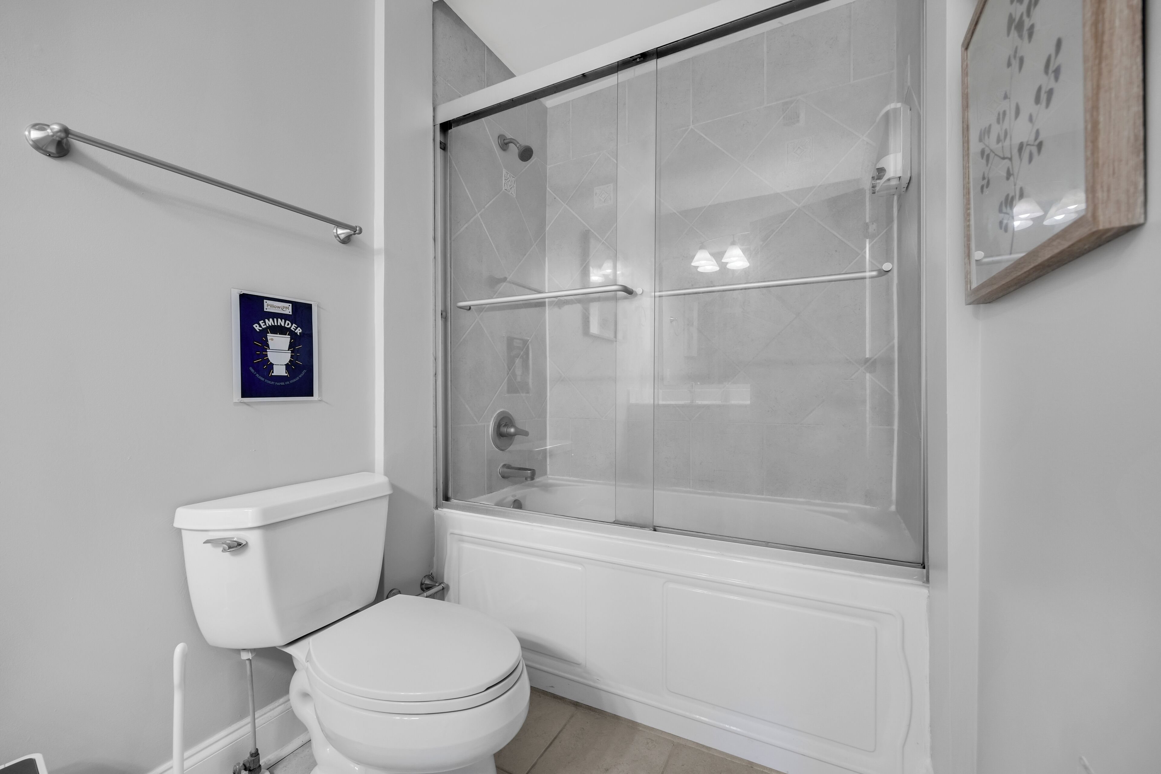 Une salle de bain équipée de toilettes, d’une douche à parois de verre et d’une barre d’appui.