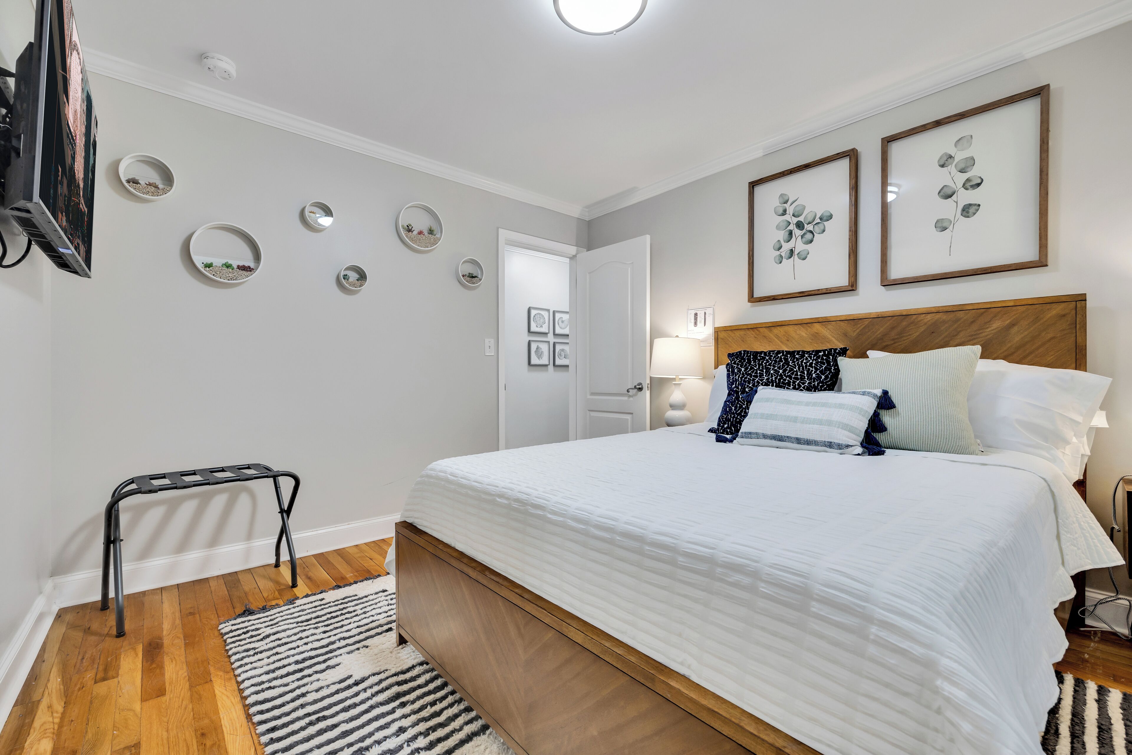 A bedroom with a bed, a TV, a small table, and wall decorations.