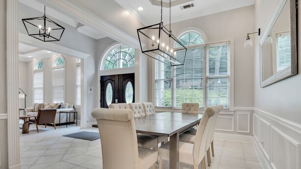 A dining area with a large table, multiple chairs, and pendant lighting. - Conference House Near Emory/CDC w/ Arcade (Atlanta)