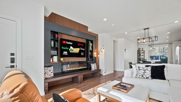 A modern living room with a flat-screen TV displaying streaming services, a fireplace, and a white sofa. - Roam Ski Den R5949|Ski Retreat|Spacious Family Loc (Mountain Green)