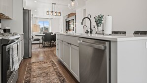 Una cocina moderna con electrodomésticos de acero inoxidable, una isla central e iluminación colgante.