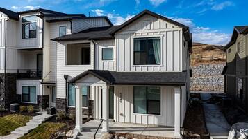 Une maison moderne à deux étages, avec des fondations en pierre, un porche avant couvert et le numéro « 5049 » sur la porte.