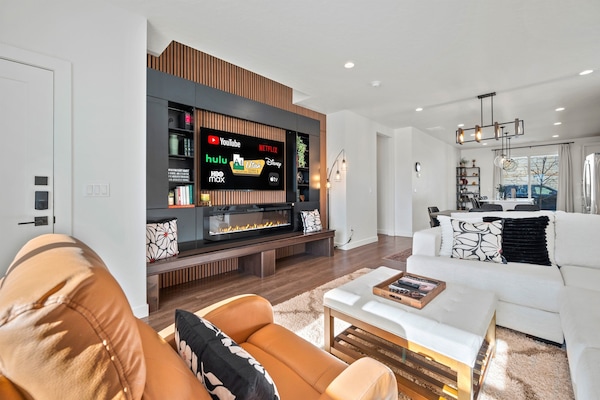 The living room Is beautiful and inviting, with the sectional and a smart TV with an electric fireplace.