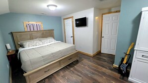 A bedroom with a bed, a TV, a guitar, and a wardrobe. - Waterfront 4BR House w/ Sunset View & Fenced Yard (Saint Joseph)