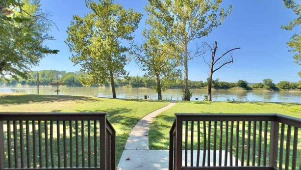A wooden deck with a pathway leading to a lake, surrounded by trees. - Waterfront 4BR House w/ Sunset View & Fenced Yard (Saint Joseph)