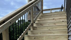 Una escalera de madera con barandilla de metal que lleva a una terraza.