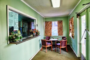 Una habitación con ventana, una mesa con sillas y un tablón de anuncios.