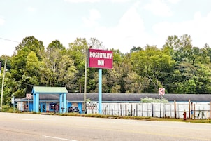 A blue building with a sign reading "Hospitality Inn" and a "No Parking" sign.