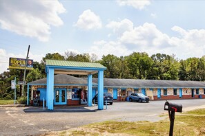 Un motel con fachada azul y una gasolinera adosada, con un letrero de Coca-Cola.