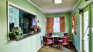 A room with a window, a table with chairs, and a bulletin board with posted notices. - Hospitality Inn (Selma)