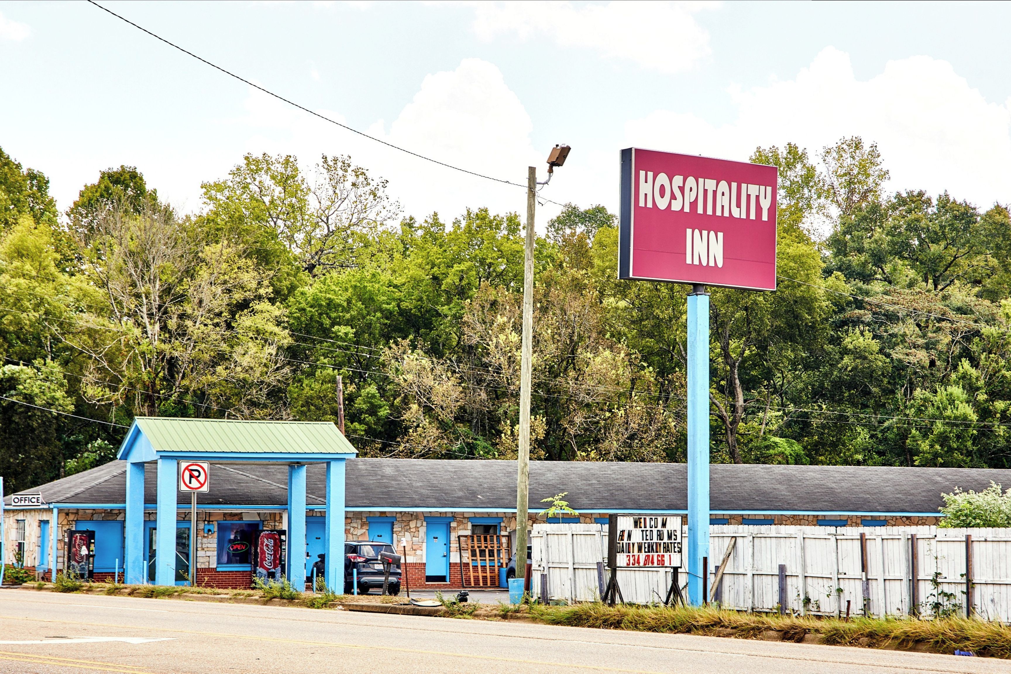 A blue building with a sign for a Hospitality Inn.