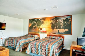 A hotel room with two beds, a television, a desk, and a painting of a sunset over palm trees. - Hospitality Inn by Hotel O Selma US 80 (Selma)