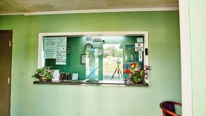 A reception desk with a green wall, a clock, and various signs including a photo ID requirement and a no smoking policy. - Hospitality Inn (Selma)