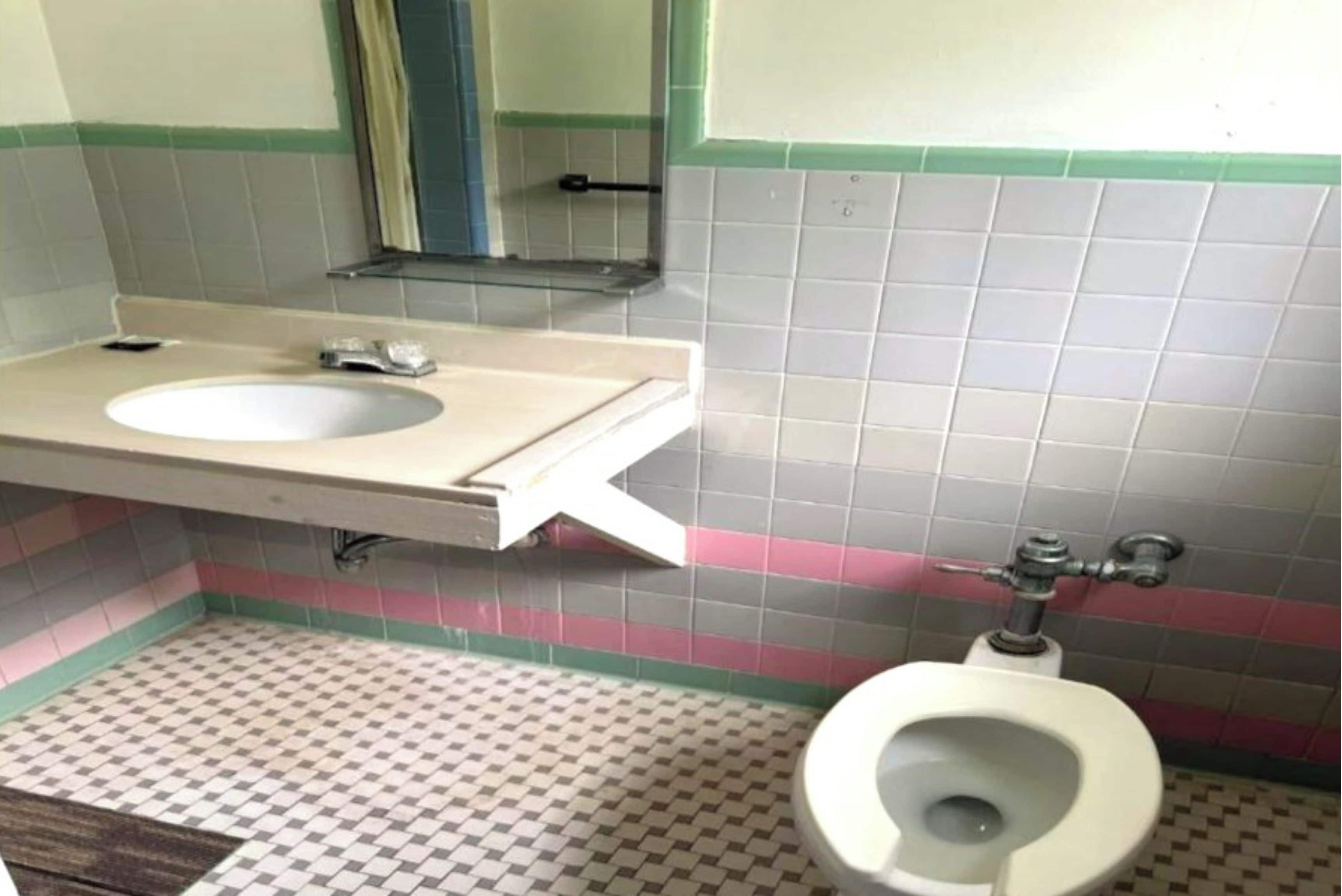 Un baño con lavamanos, espejo e inodoro.