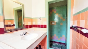 A bathroom with a white sink, a mirror, and tiled walls in various colors. - Hospitality Inn by Hotel O Selma US 80 (Selma)