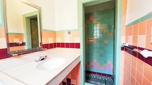 A bathroom with a white sink, a mirror, and tiled walls in various colors. - Hospitality Inn by Hotel O Selma US 80 (Selma)