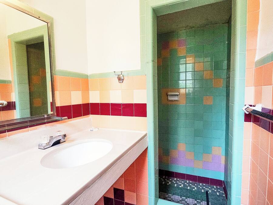 A bathroom with a white sink, a mirror, and a tiled shower area.