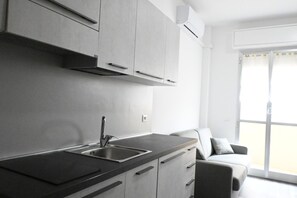 A modern kitchen with a built-in sink, cabinets, and a sliding glass door leading to a balcony.