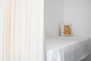 A bed with a white sheet and a pillow with text.
