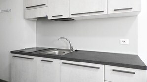 Une cuisine moderne avec des meubles blancs, un plan de travail noir et un évier en acier inoxydable.