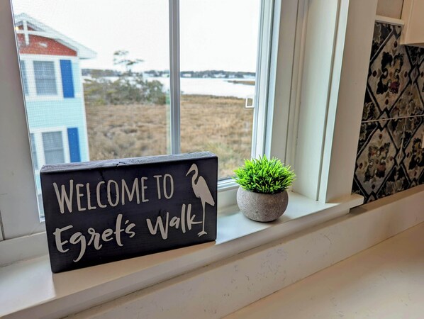 A welcome sign with a bird silhouette and a small potted plant on a windowsill. - New Home with Sound Views & Central Location! (Kill Devil Hills)