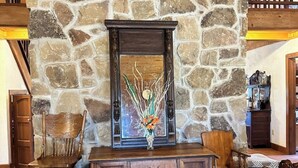 A stone fireplace with a wooden mantel, flanked by two wooden chairs and a wooden cabinet below. - Rustic but elegant 4-bedroom farmhouse in Canton with WiFi and AC (Canton)