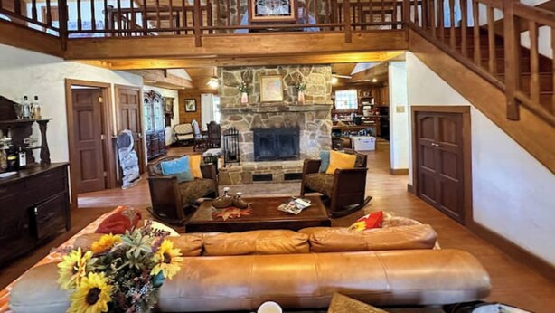 A spacious living room with a stone fireplace, leather sofas, and a wooden staircase. - Rustic but elegant 4-bedroom farmhouse in Canton with WiFi and AC (Canton)