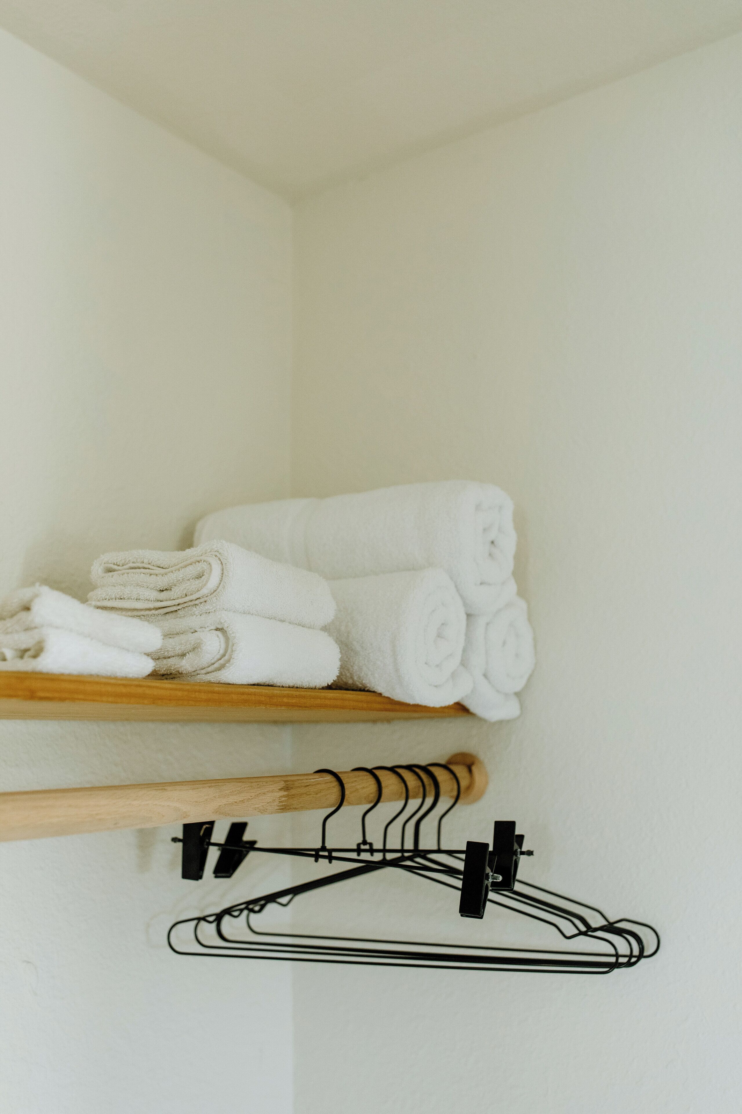 A storage area with shelves holding folded towels and a set of black hangers.