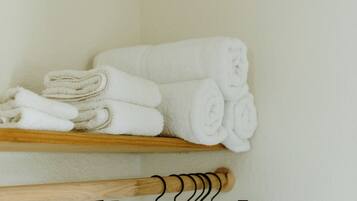 A storage area with shelves holding folded towels and a set of black hangers.