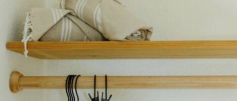 A wooden shelf with folded towels and a metal hanger.
