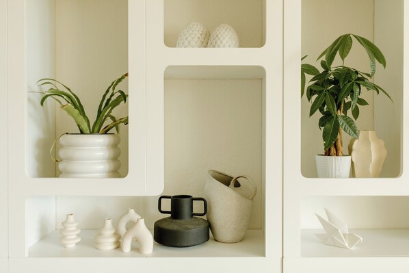 Una repisa con varios objetos decorativos, incluyendo jarrones, una planta en maceta y una escultura.